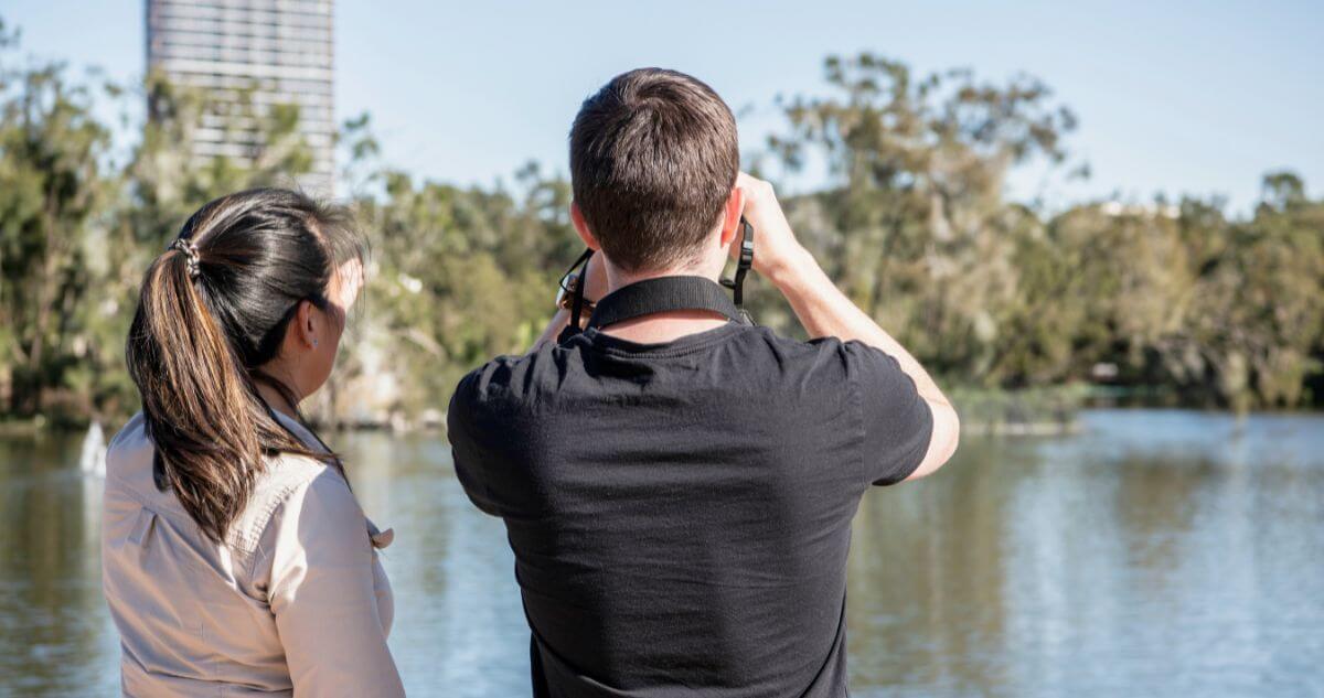 Image of two people bird watching over a lake