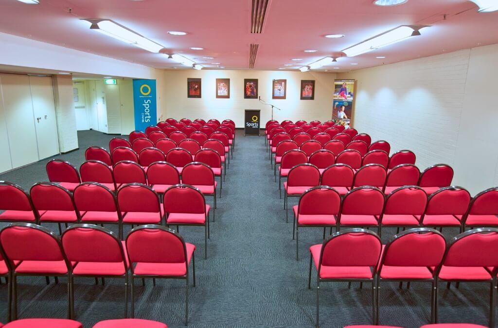 Acacia and Banksia conference room, large room lined with red chairs and a microphone and podium at the front